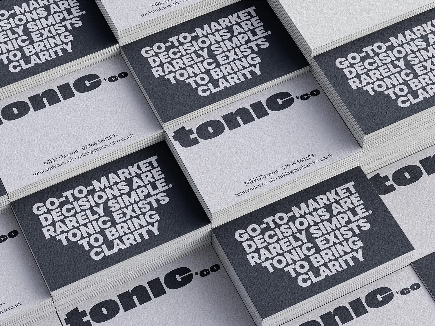 Stacked business cards for Tony + Co featuring bold text that reads "Go-to-market decisions are rarely simple. Tonic exists to bring clarity." Contact details for Nikki Dawson are printed in smaller text on the cards.