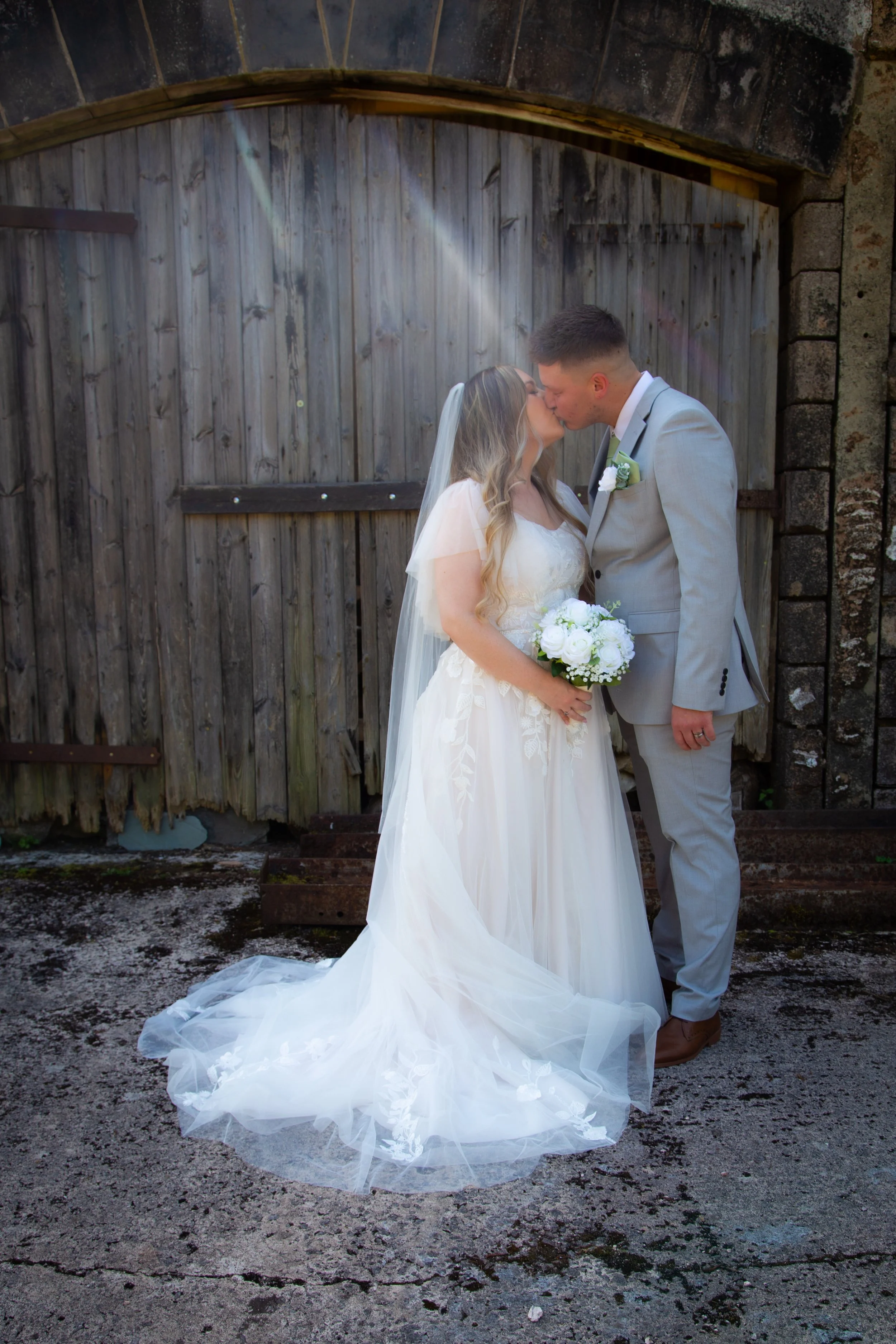 standing in front of the barn at Bickley Mill, Torbay the couple share a kiss