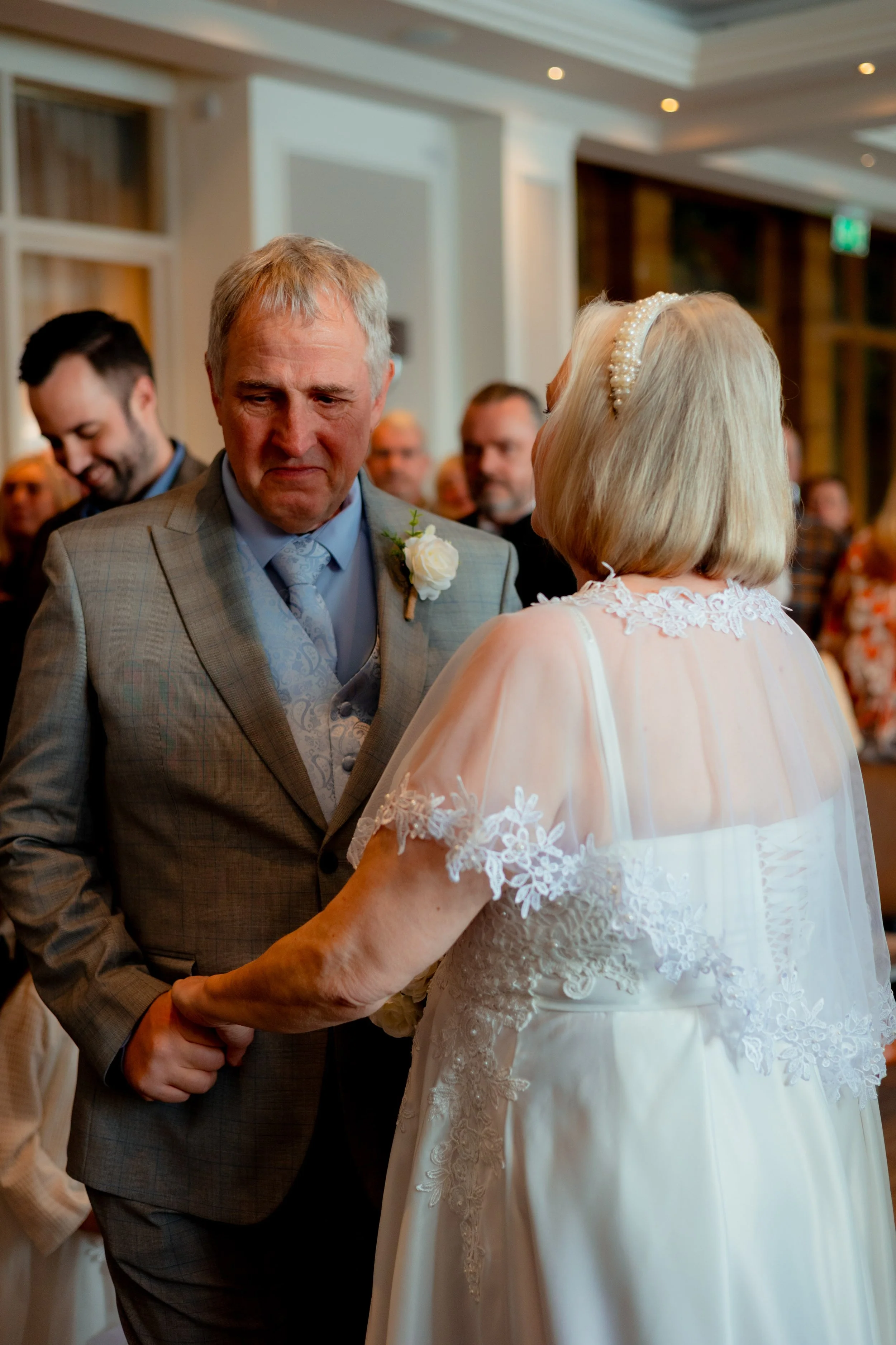 Candid wedding photography in Somerset capturing older couple dancing during wedding reception with guests in background