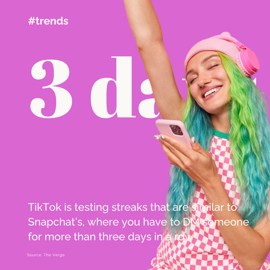 A woman with blue and green hear, wearing a pink beanie and pink headphones, holding a pink smartphone