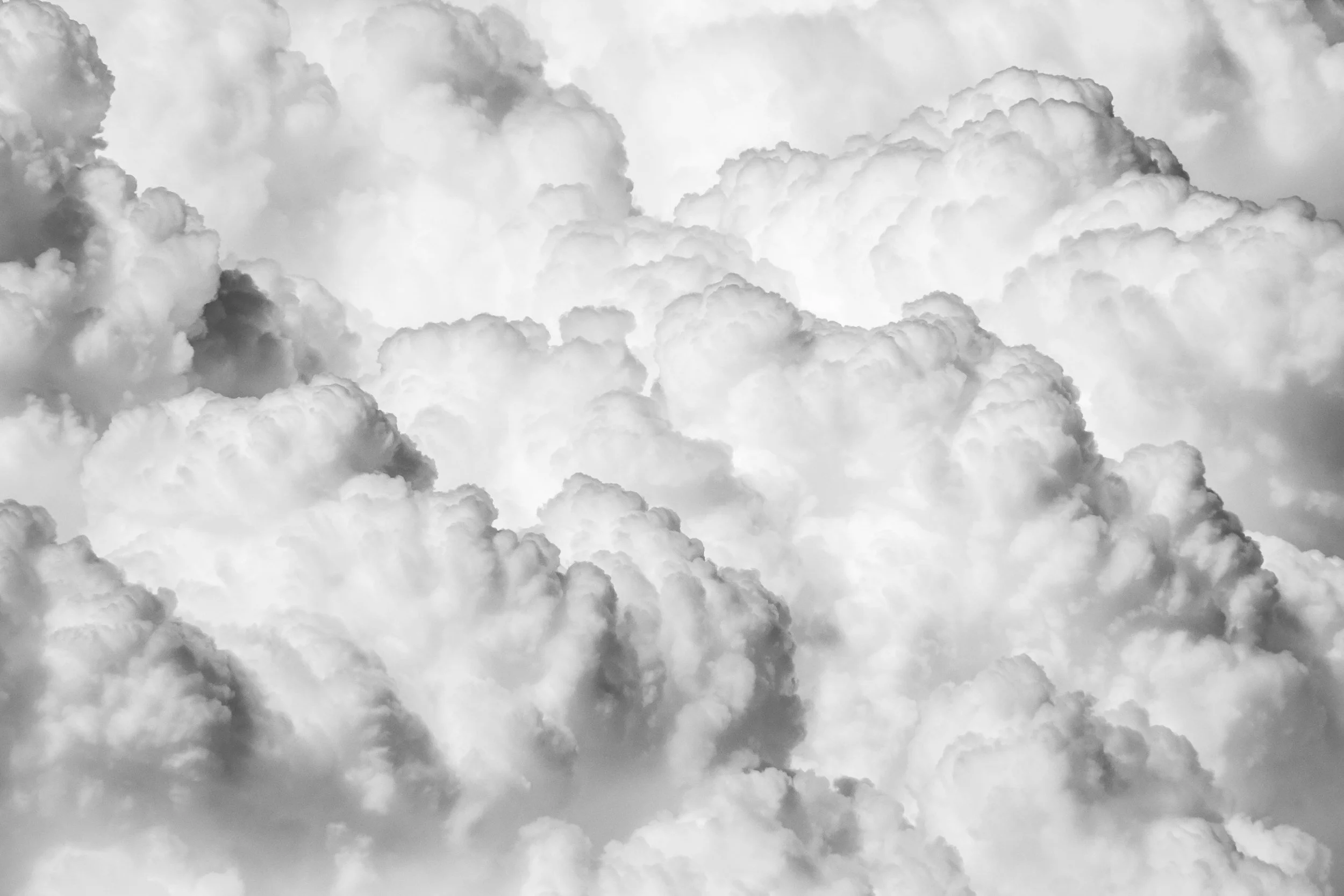 Black and white photograph of large, fluffy clouds in the sky.