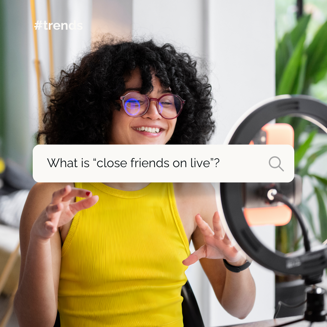 Women with curly black, hair, glasses and a yellow tank top, talking into a smartphone, inside a ring light