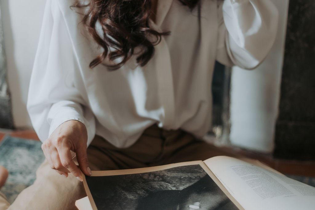 Une femme tient un livre ouvert montrant une photographie en noir et blanc.