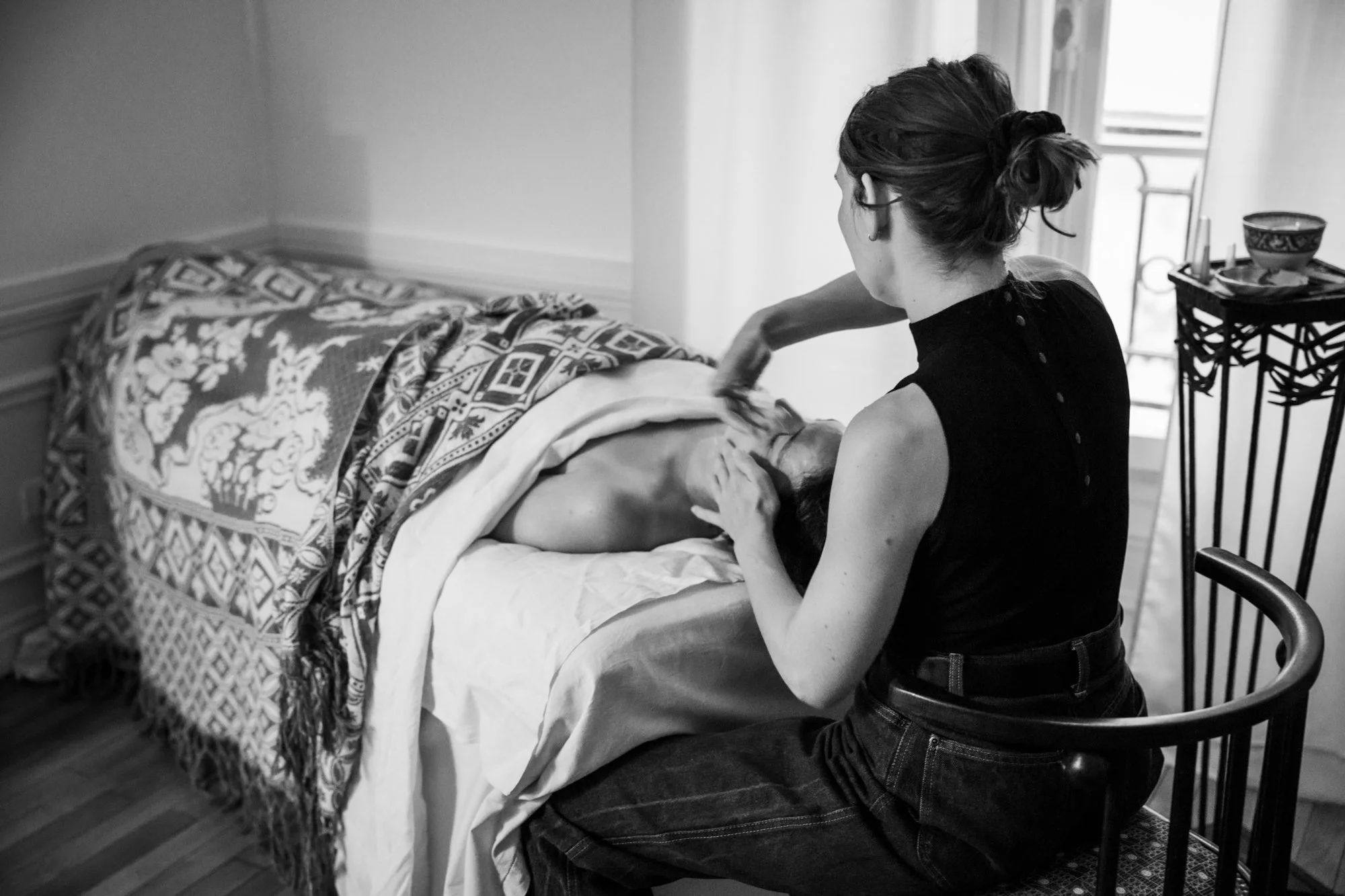 Femme donnant un bain à un enfant sur un lit dans une pièce bien éclairée.