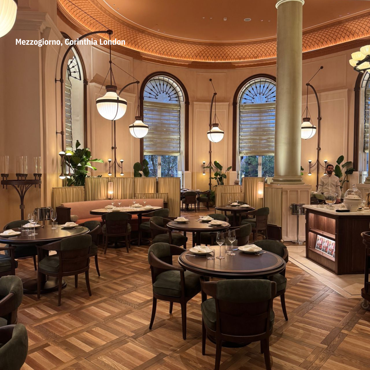 A cozy wooden bar with a selection of bottles on shelves, several bar stools, and warm lighting in a dimly lit room.