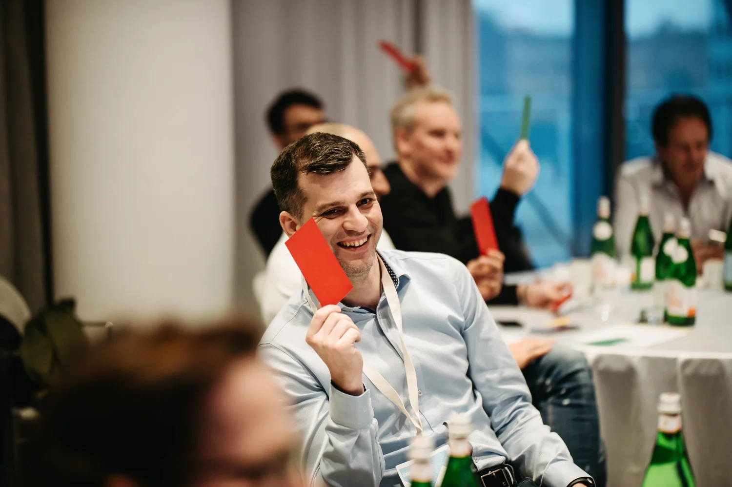 A member smiling and holding up a voting card during a CEO CF group session.