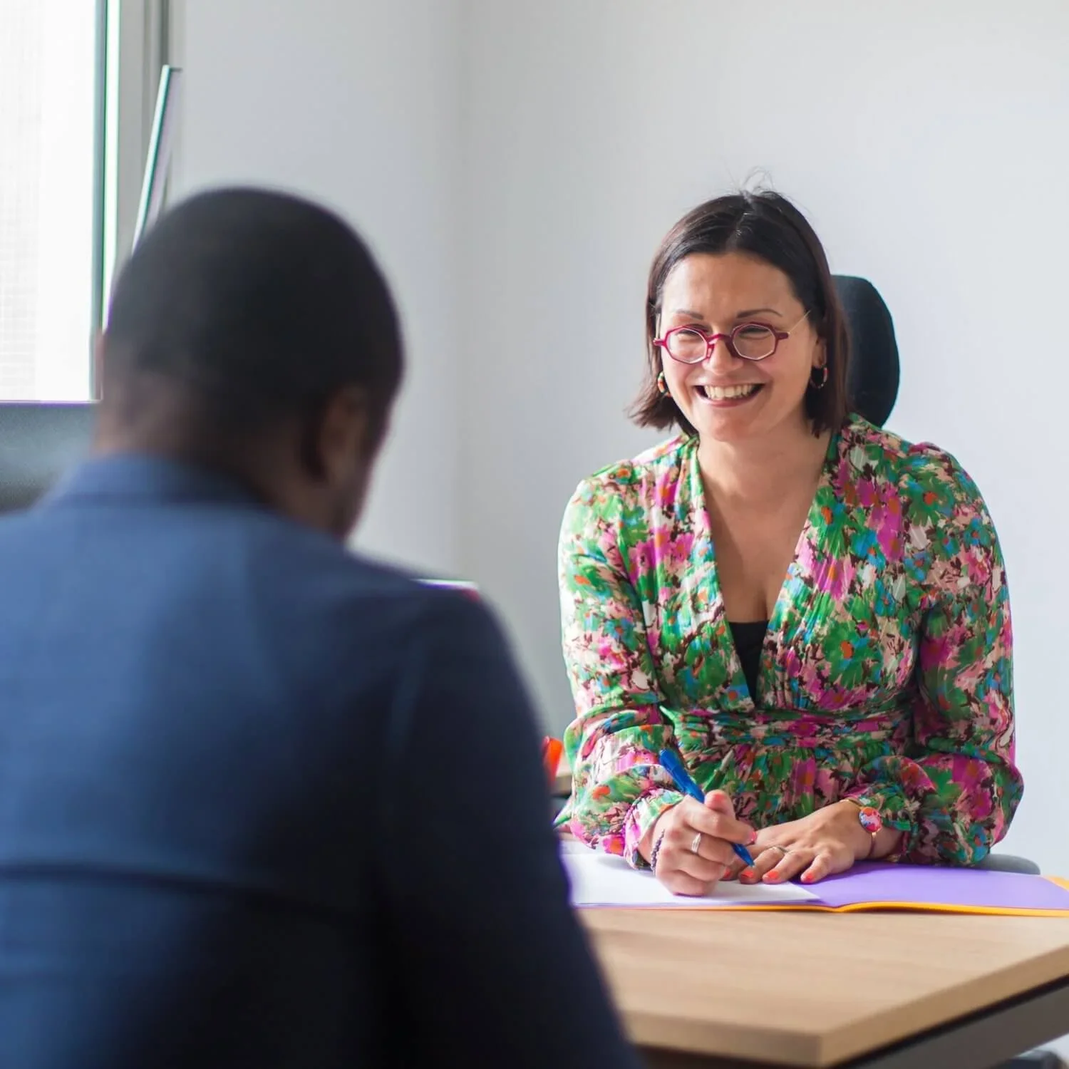 Une avocate échange avec un client à son bureau.