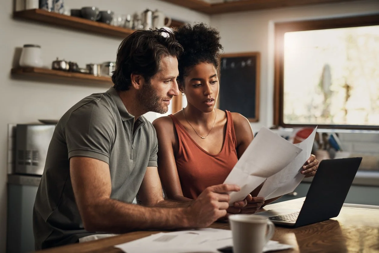 Couple calmly reviewing household bills at the kitchen table, using focused time and shared tasks to work through a money conflict.
