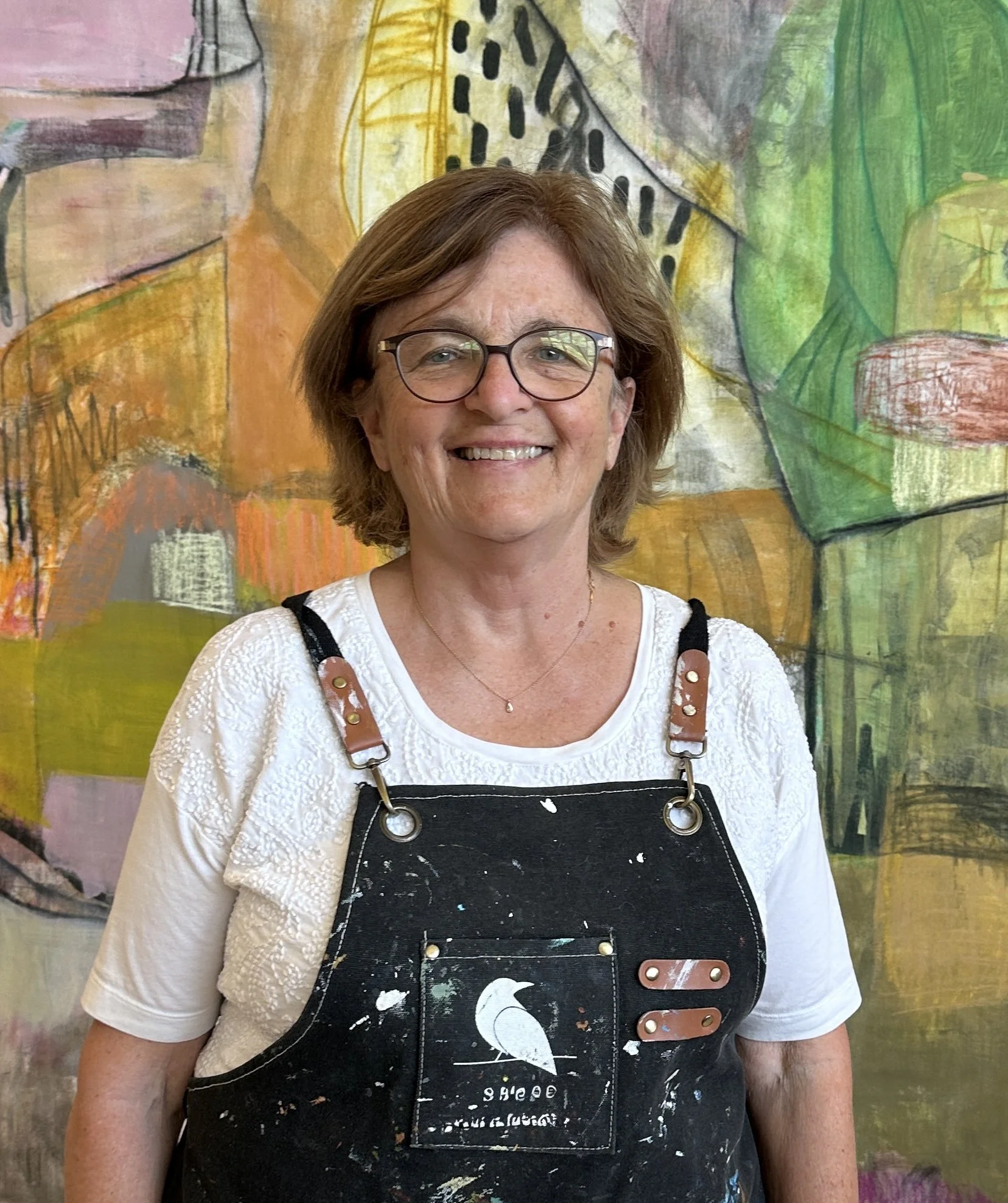 Image of Artist Mary Sirody with her Dynamic Abstract Painting behind her in greens, pinks, oranges and lavender colors.