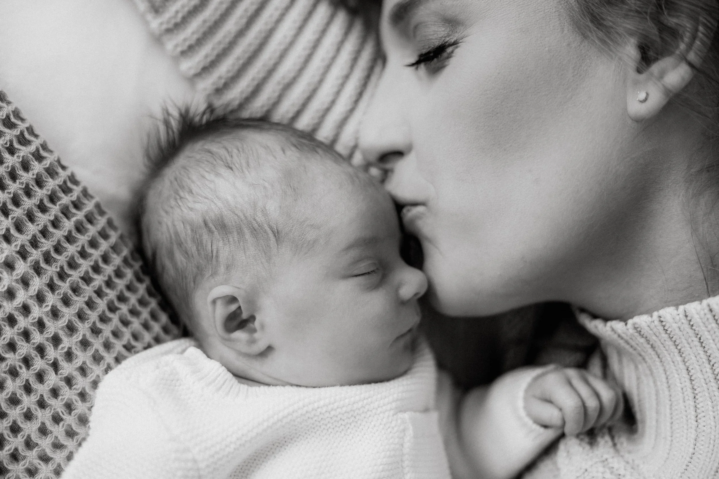 Mom kissing baby at home for newborn photo in bedroom