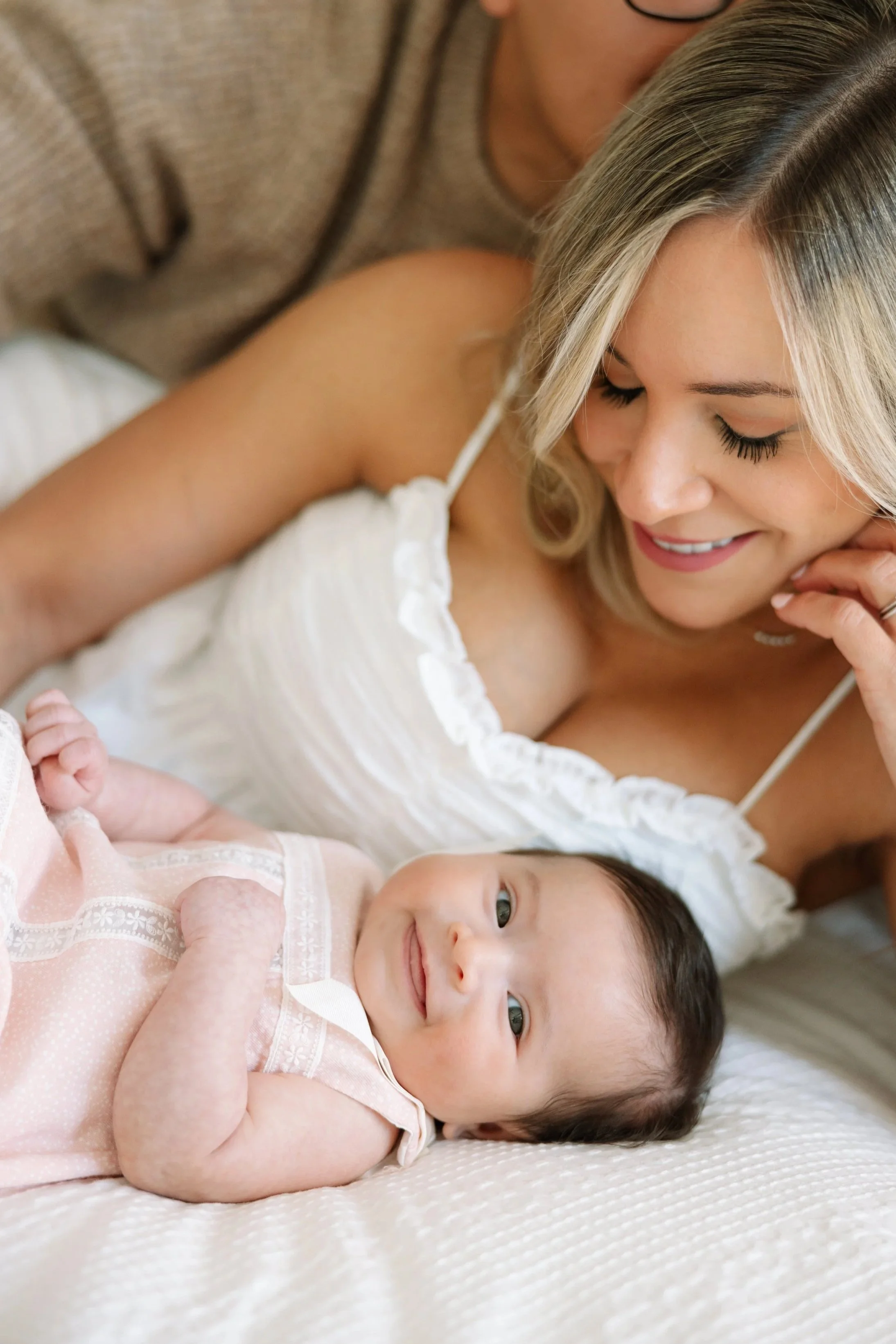 Mother cuddling her newborn in a softly lit bedroom during a Nashville in-home session