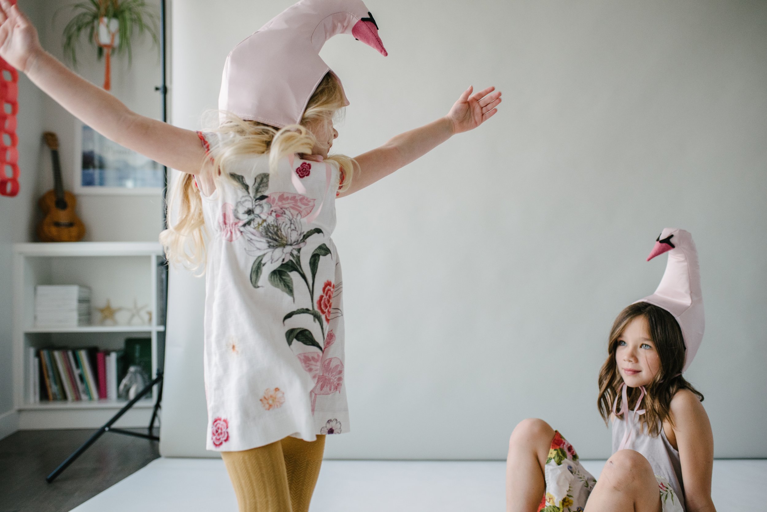 Two girls wearing a bird Hat and playing