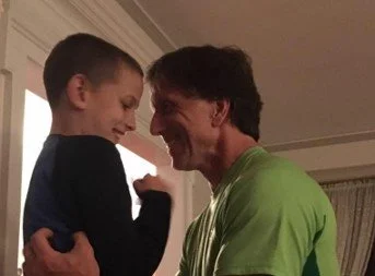 A man and boy sharing a joyful moment, nose-to-nose, inside a home.