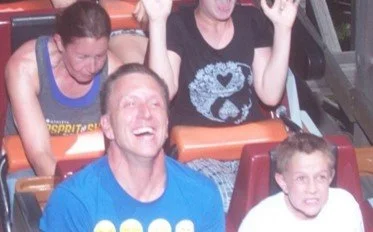 Group of people at an amusement park or fair, enjoying a ride, smiling and having fun.