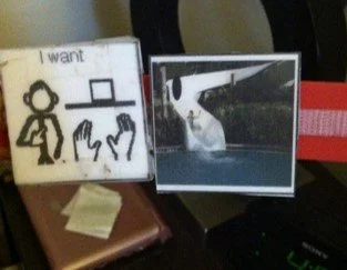 A sign with a drawing of person raising hands with the text 'I want,' next to a photograph of a white goose walking on a street.