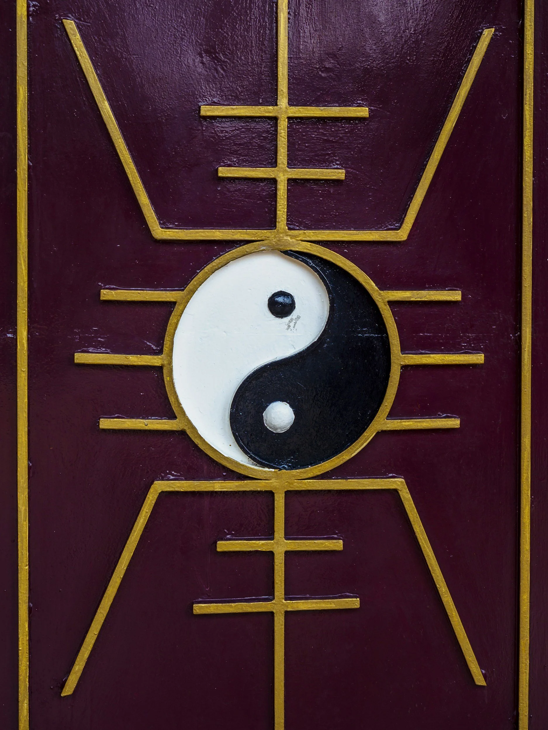 Decorative wall art featuring a yin-yang symbol with white and black halves, surrounded by a red background and gold geometric lines, and a upward-pointing arrow at the top.