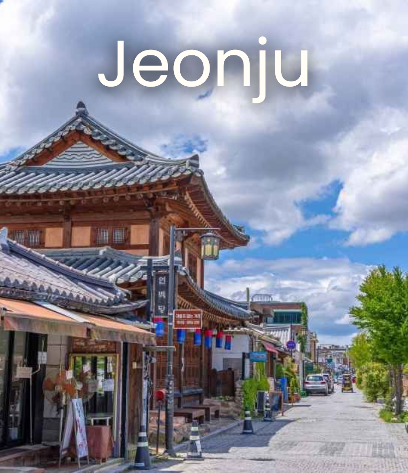 Traditional Korean-style building on a street with cars and trees, under a partly cloudy sky.