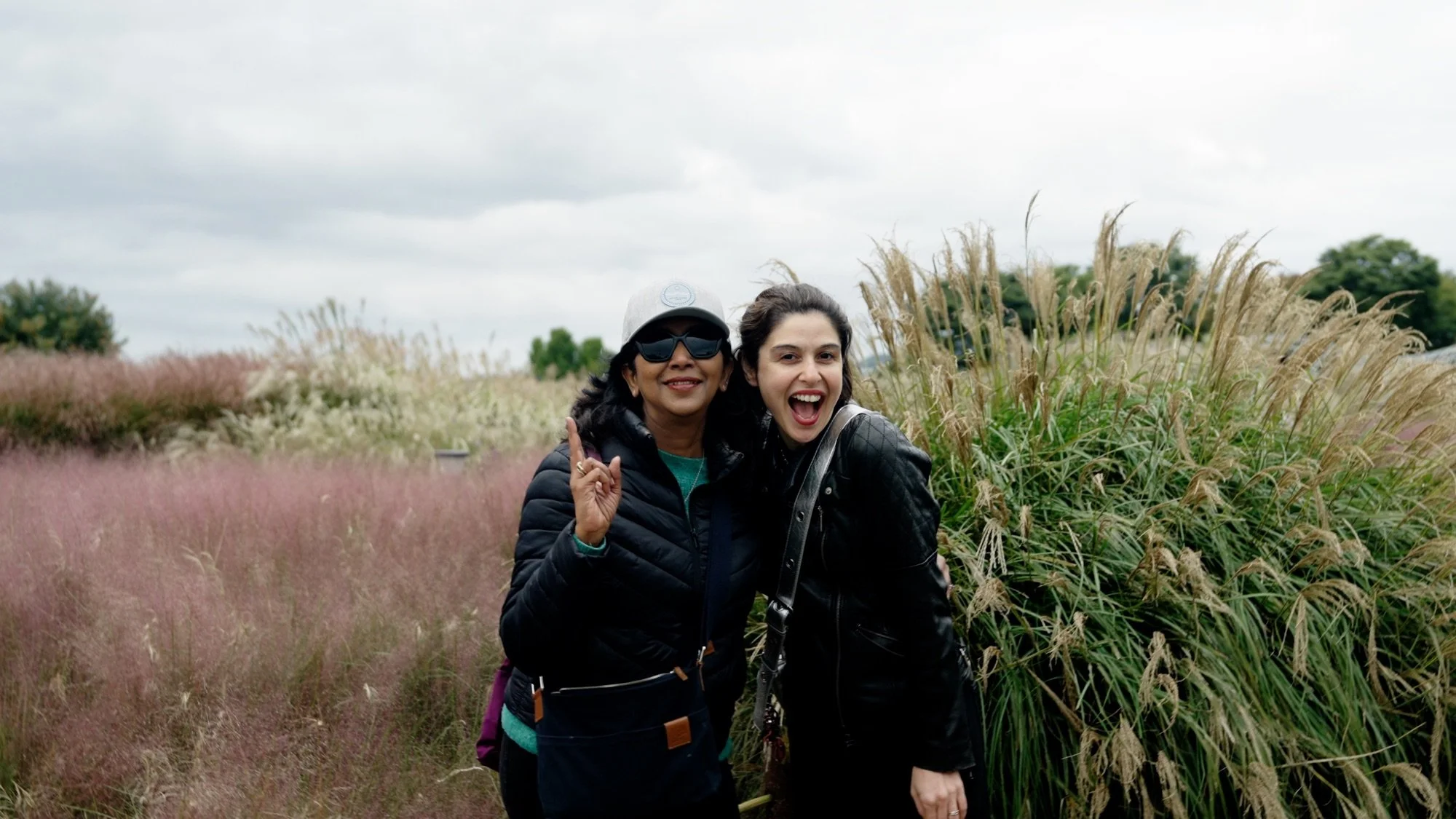Two travelers laughing in a field of pink muhly grass in Korea in autumn