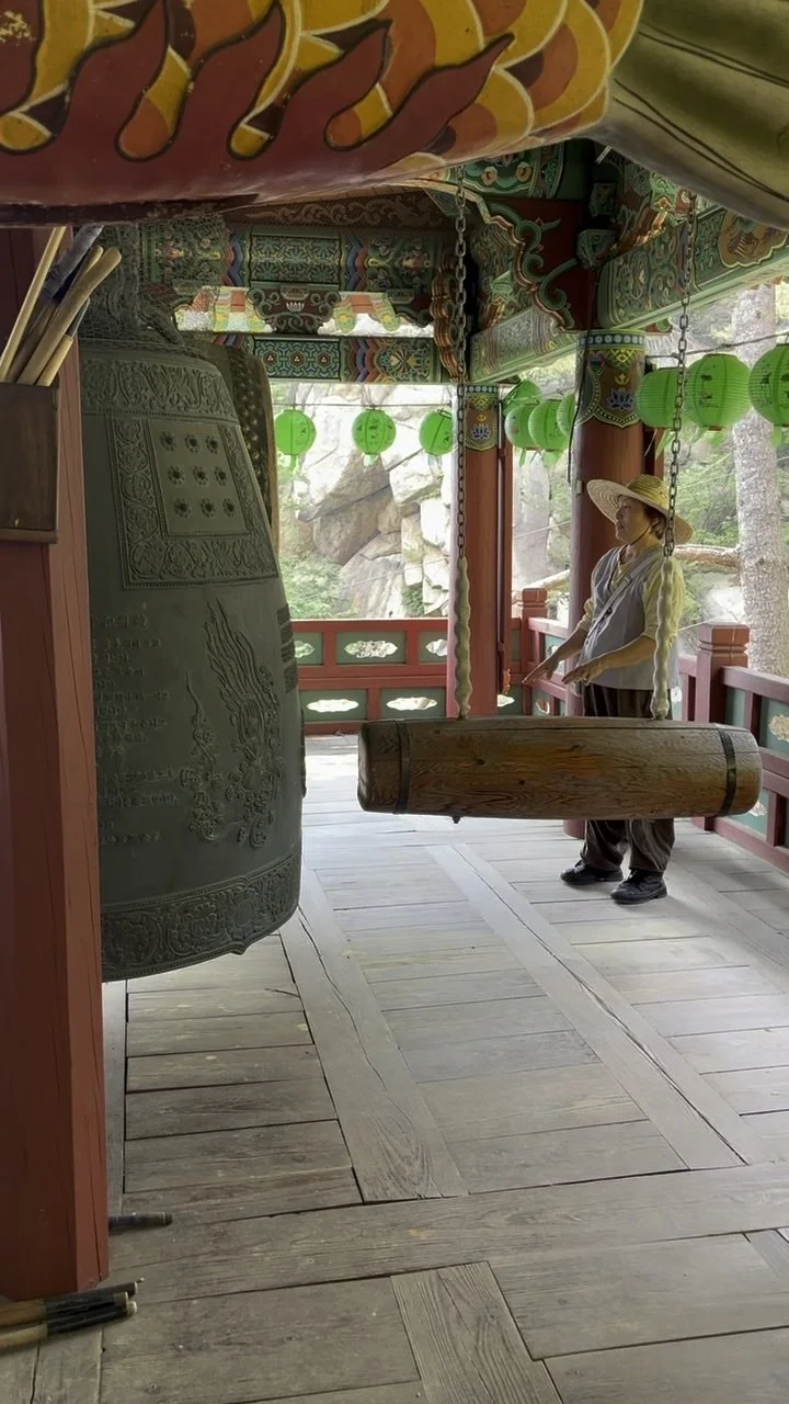 A large bronze bell inside a painted temple pavilion in Korea