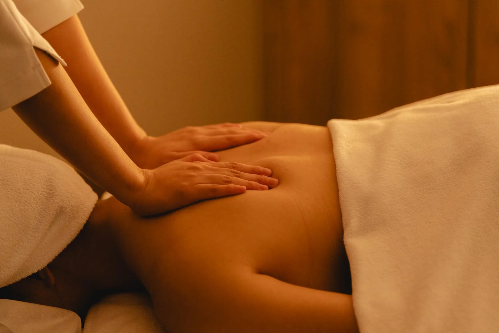 A person receiving a massage on their back in a dimly lit room.