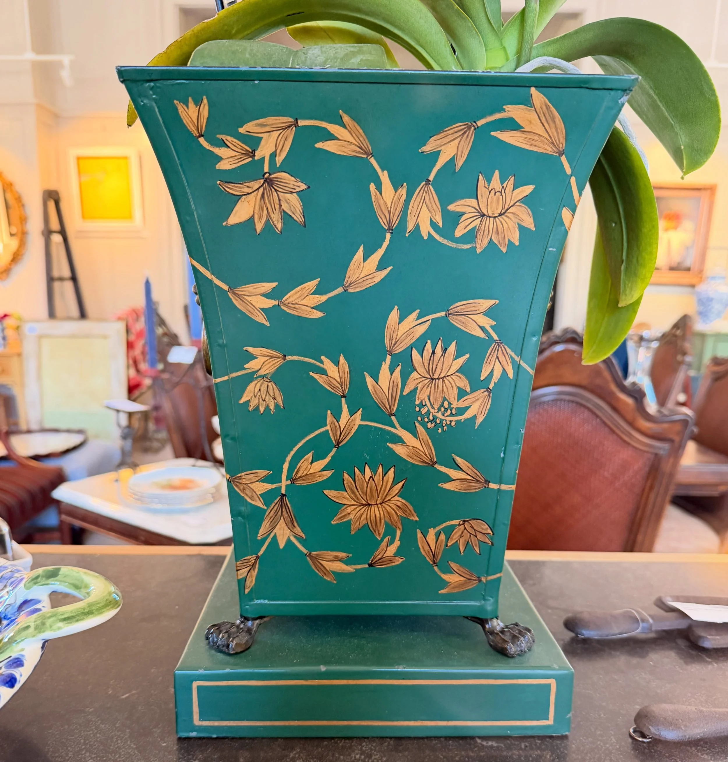 A wonderful and classic large vintage green and gold toleware cachepot.
It has a flared shape and hand painted decoration, two lions heads and lion paw feet that stand on a plinth.
Great green color! Perfect for an orchid.
13&rdquo; high x 9&rdquo; w