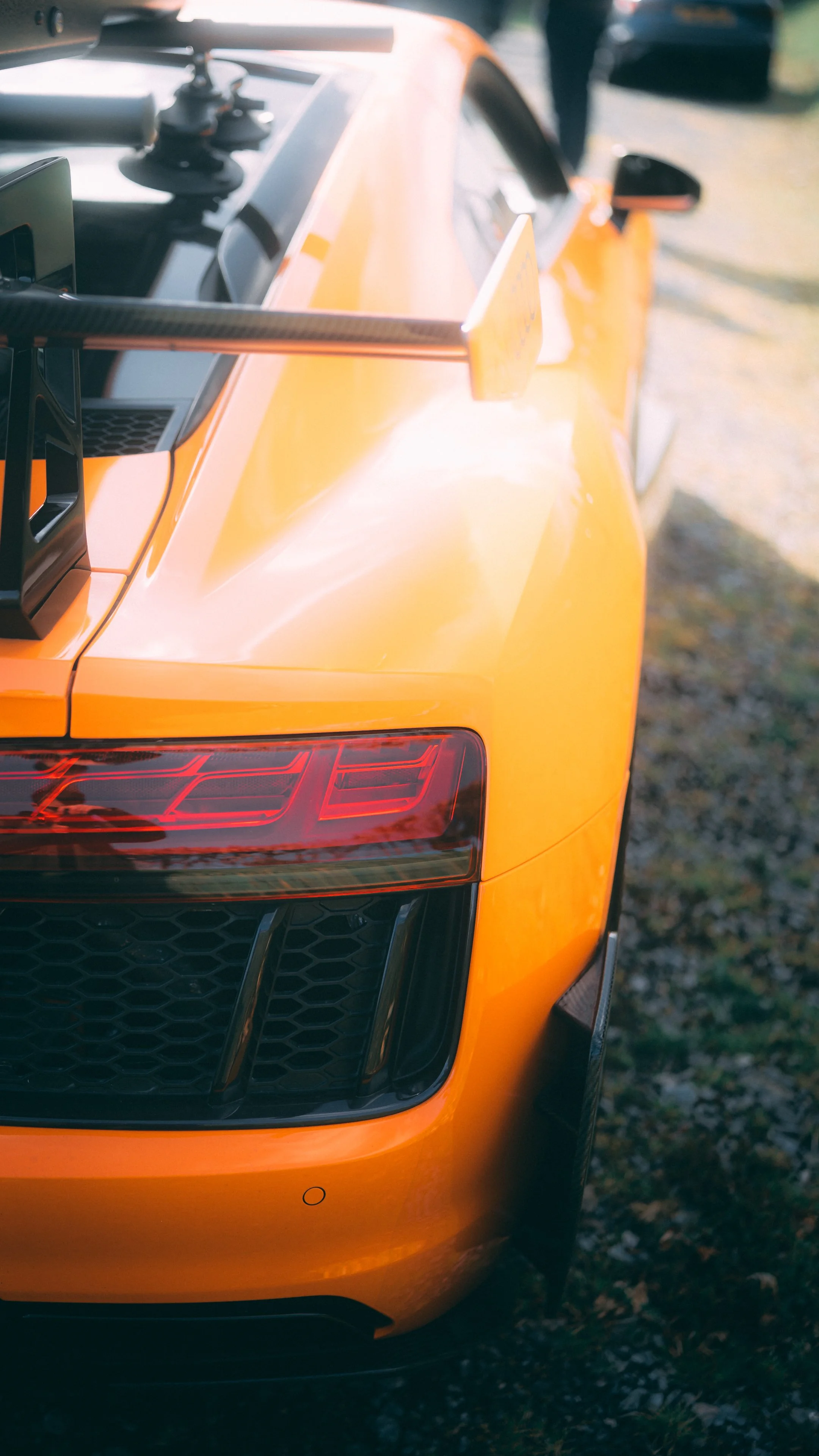 Close-up of the rear end of a yellow sports car showing part of the taillight and rear wing spoiler.