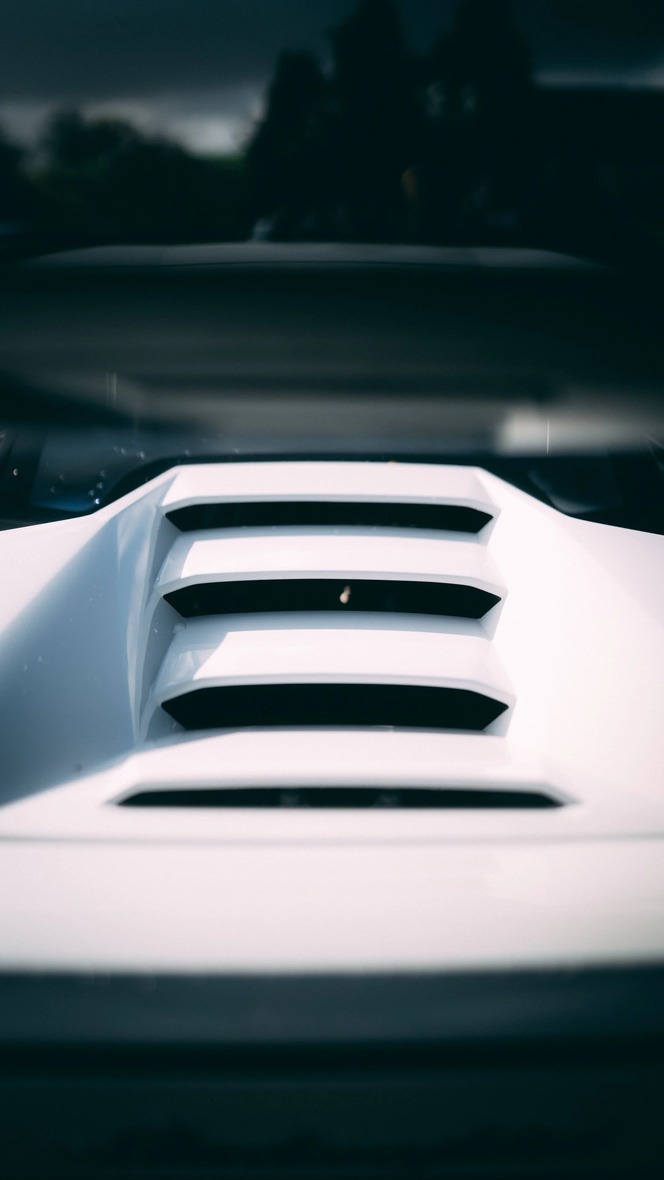 Close-up of a white automotive vent or grille with horizontal black slats, possibly from a sports or racing car.