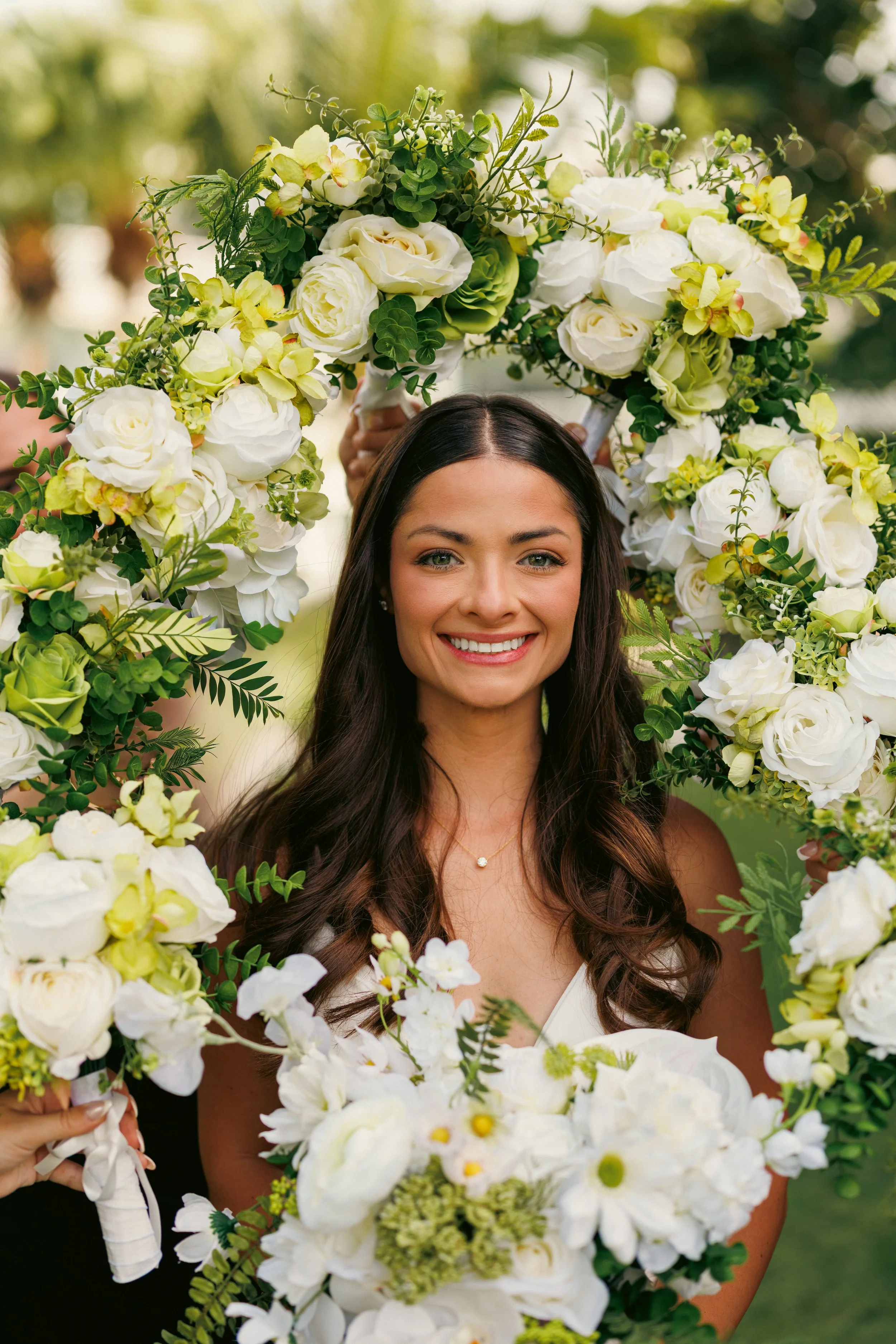 Brooke smiling behind her bouquet of white flowers on her wedding day