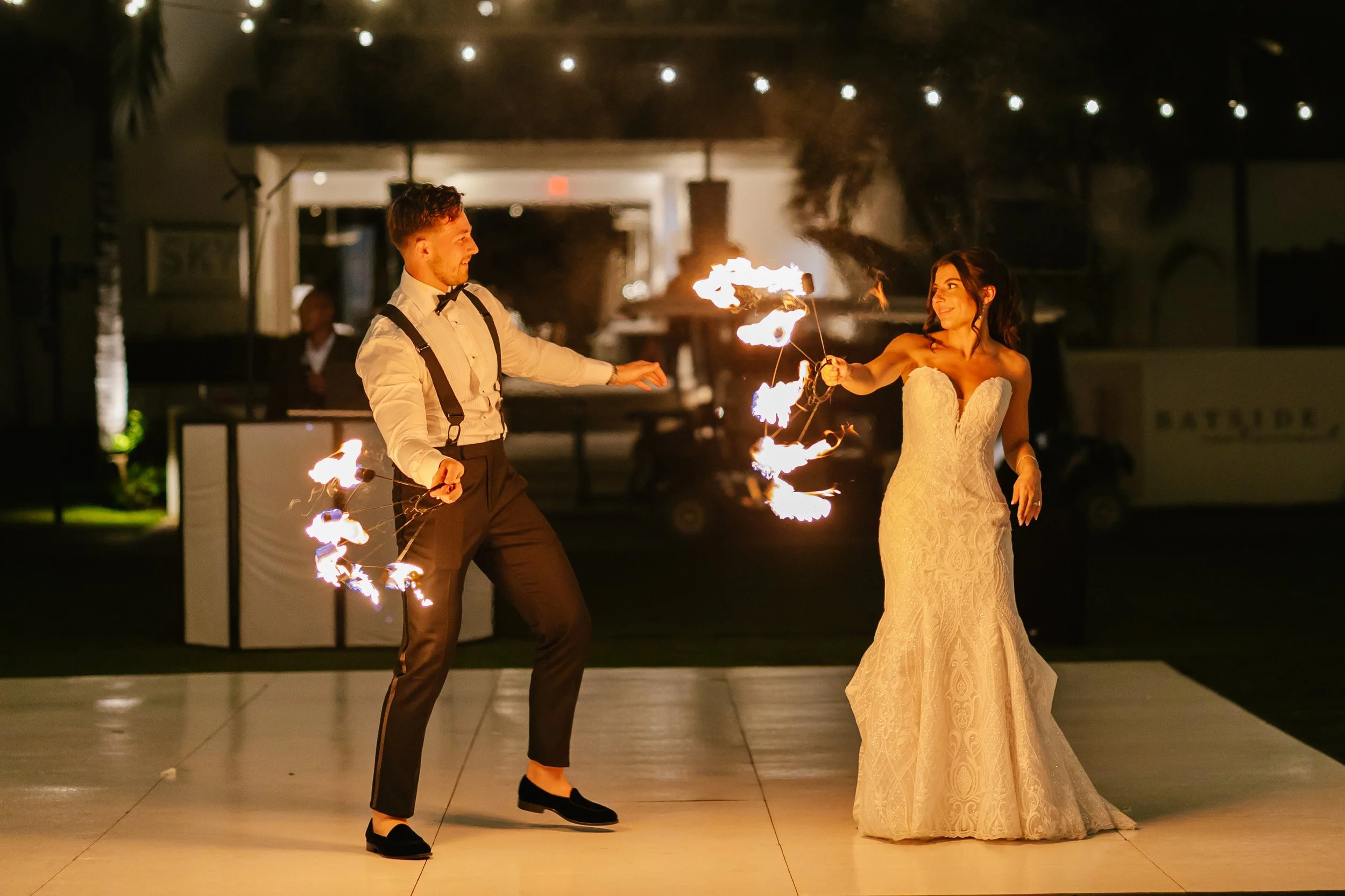 Cassie and Richie holding flaming batons during their evening wedding celebration