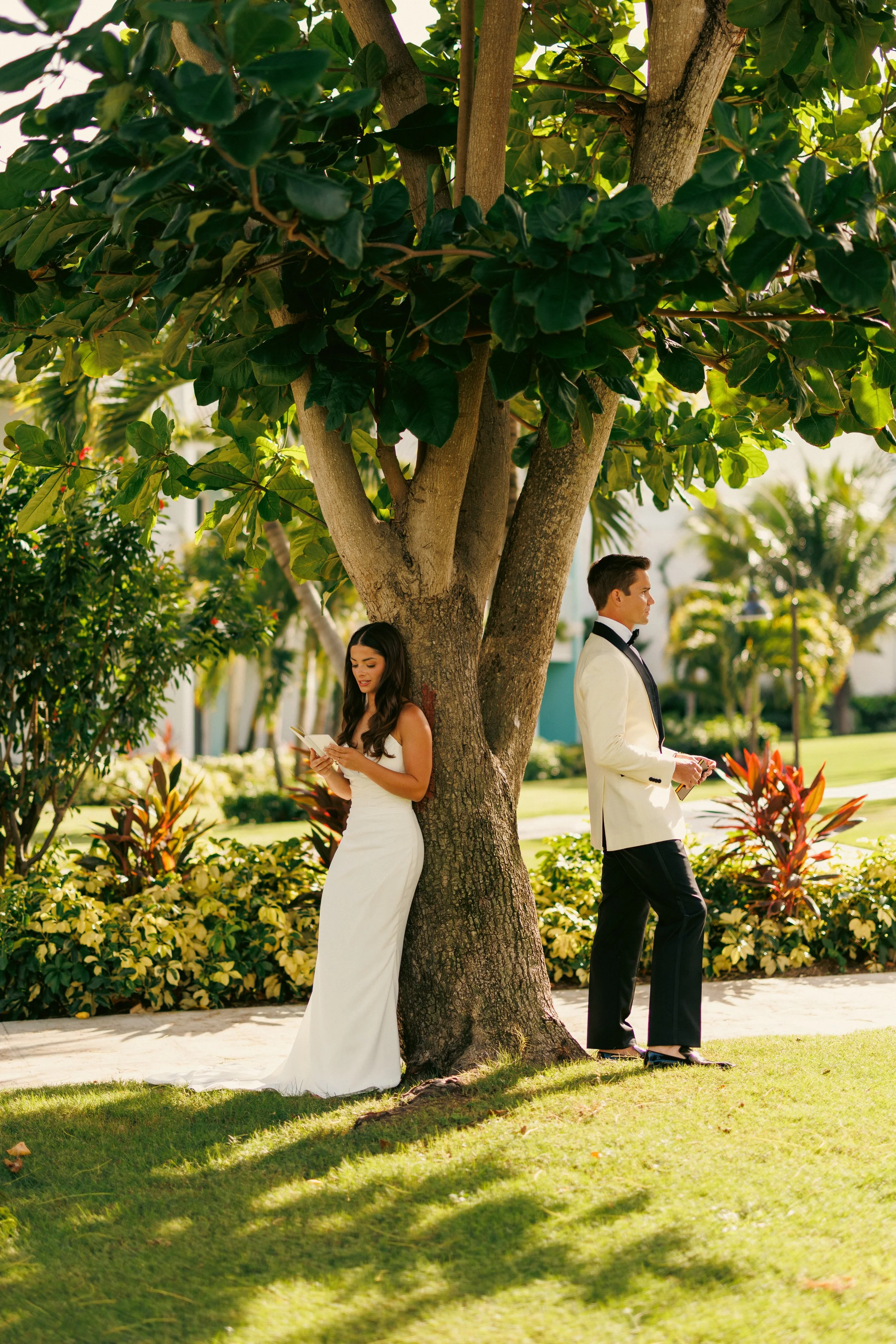 Kyle and Brooke standing on opposite sides of a tree in the resort gardens