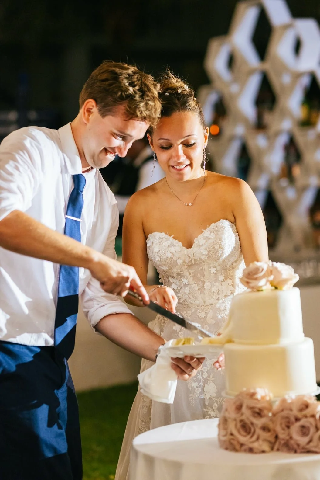 A bride and groom cutting a wedding cake together at their wedding reception.