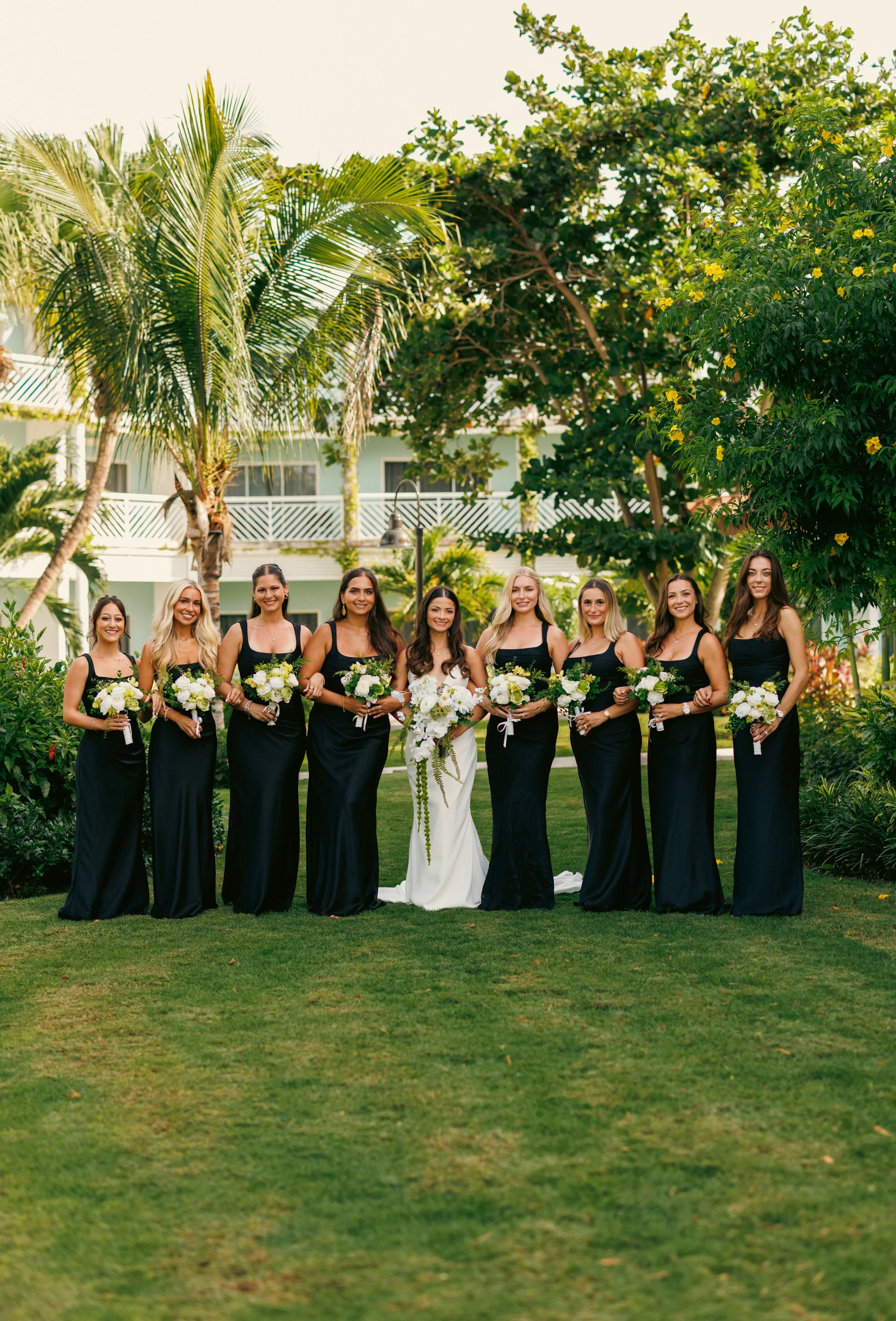 Brooke and her bridesmaids in black dresses posing on the resort lawn