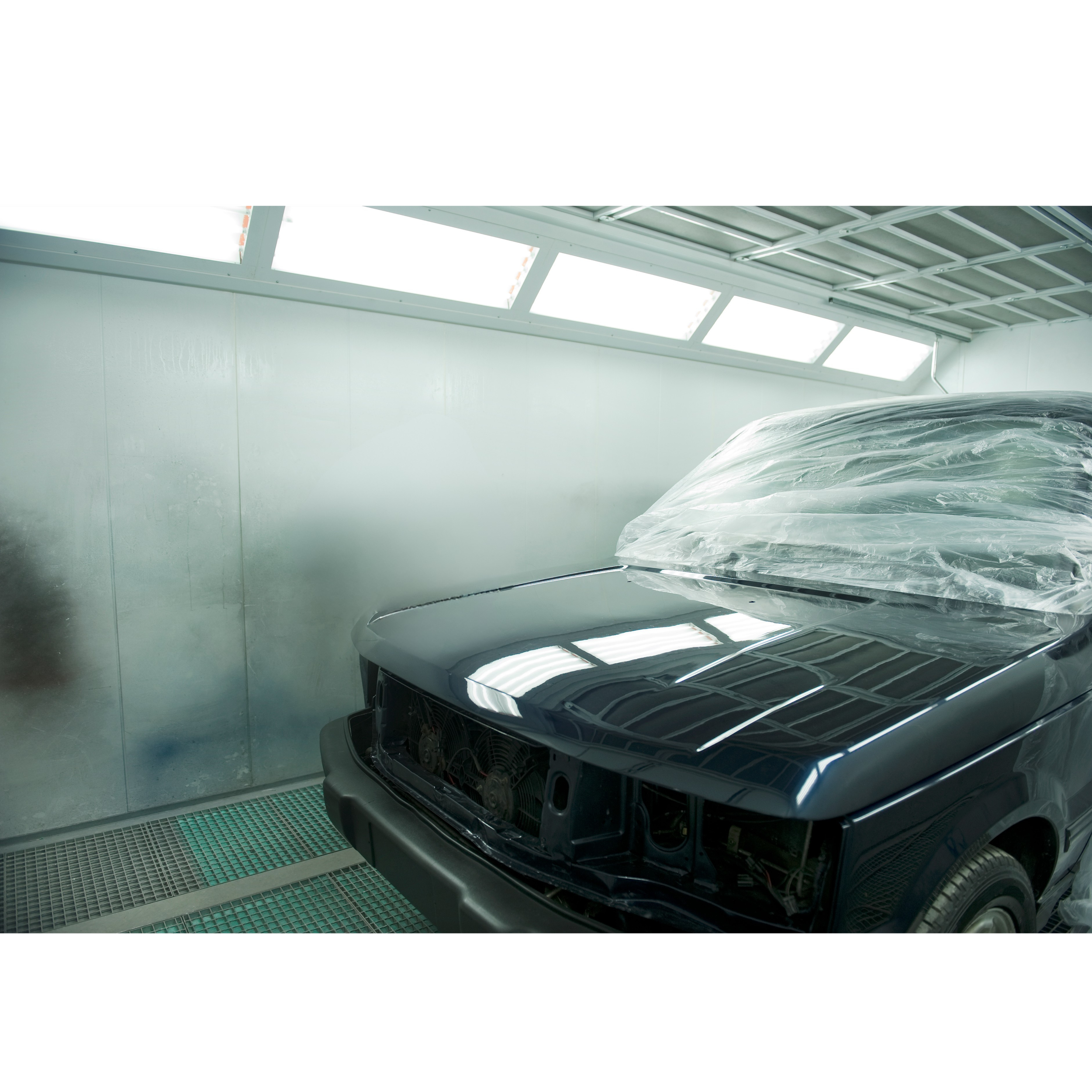 A black car in a paint room getting painted.