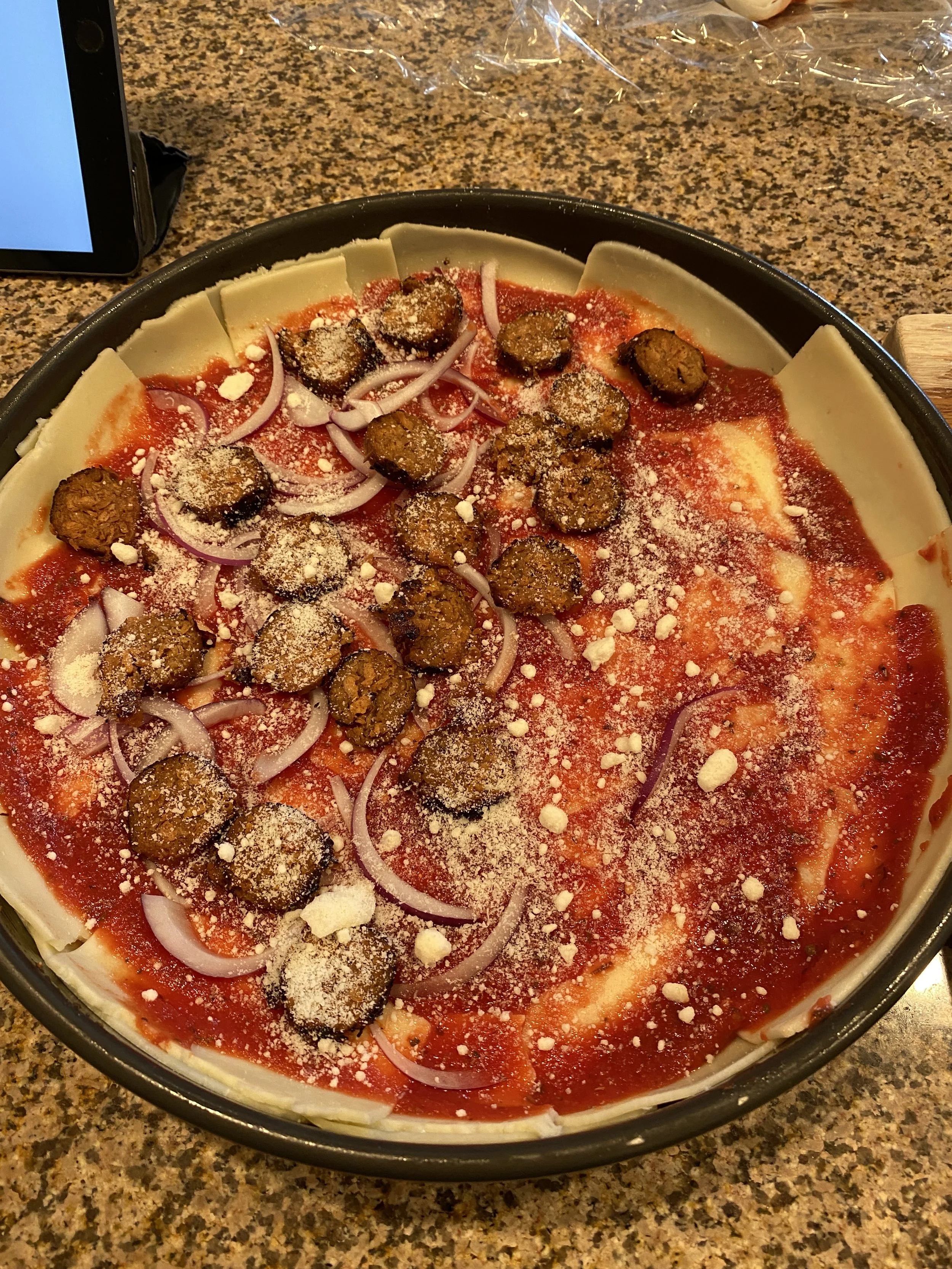 Toppings (spicy sausage and red onion on one half, just cheese on the other) and homemade sauce have been added, the oven is at 550 degrees, and the pizza is ready to go in!