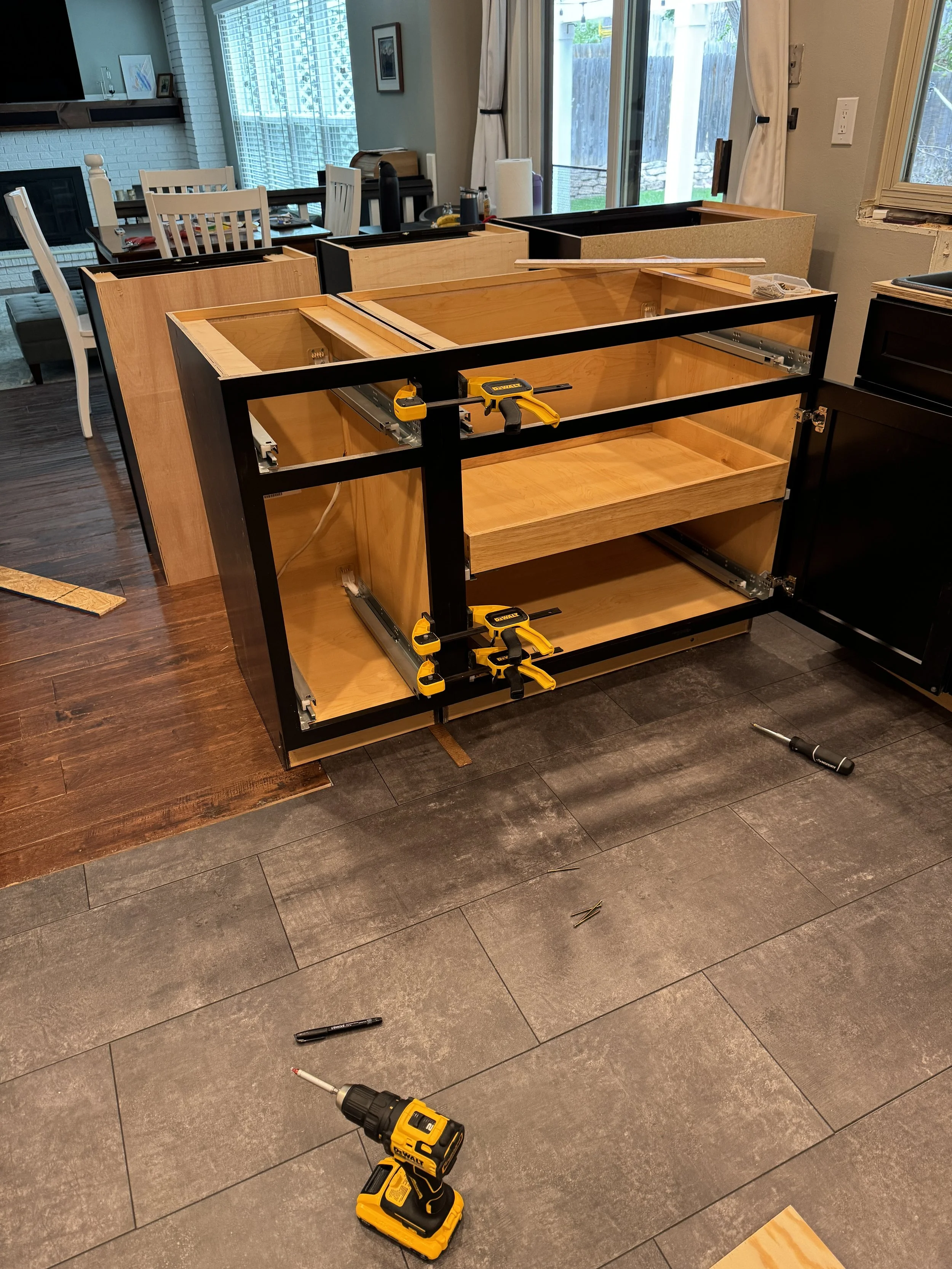 So, after a brief delay (for vacations and such), I started on getting the cabinets installed, starting with the base cabinets.  Attached 2x4's to the floor, then attached the cabinets to the 2x4's, then clamped and screwed the cabinets together.  Ro