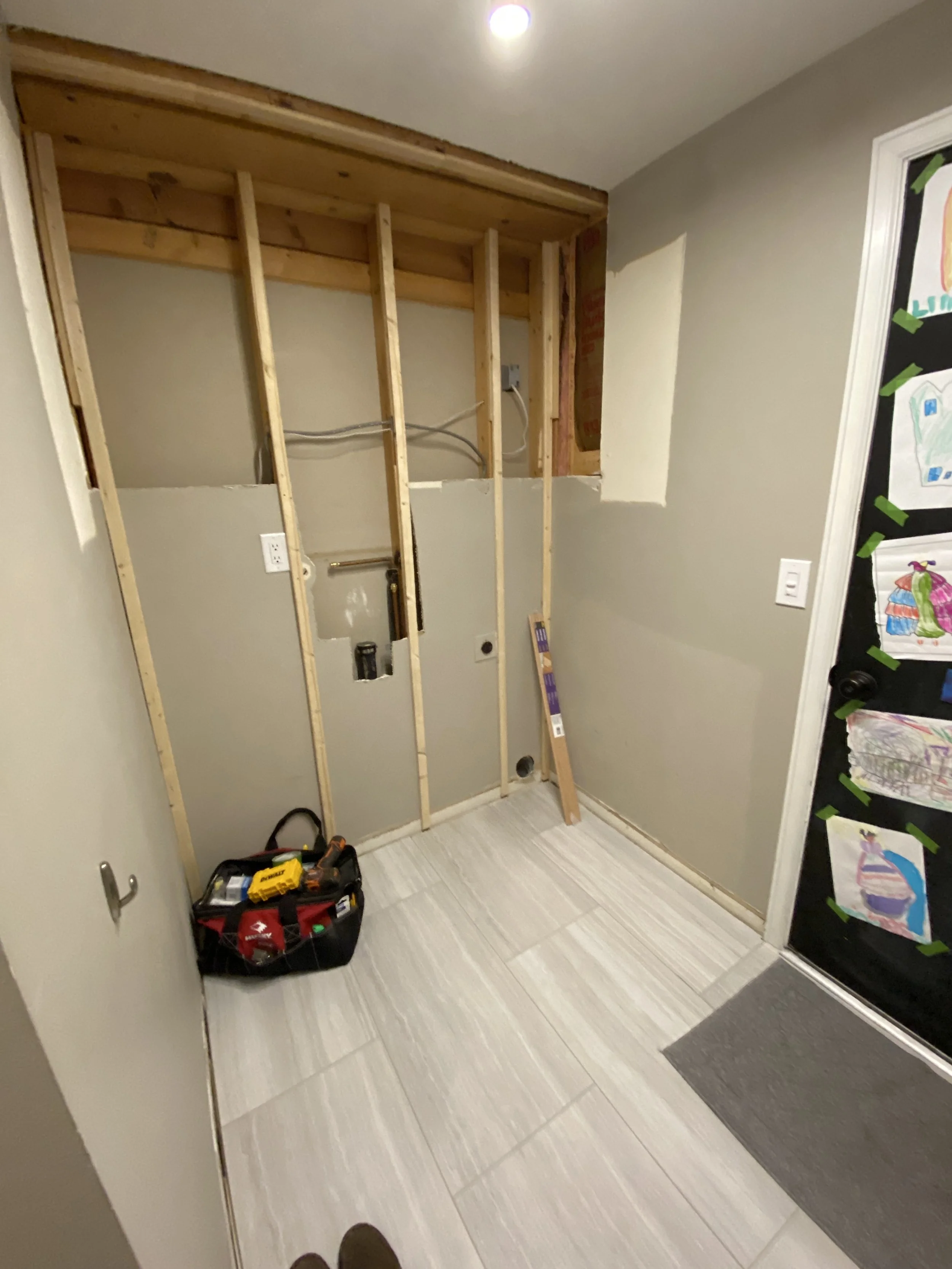 Half-wall has been removed, and 1x2's have been attached to the existing studs. Also the water supply lines and drain line for the old washer/dryer have all been re-routed and capped off.