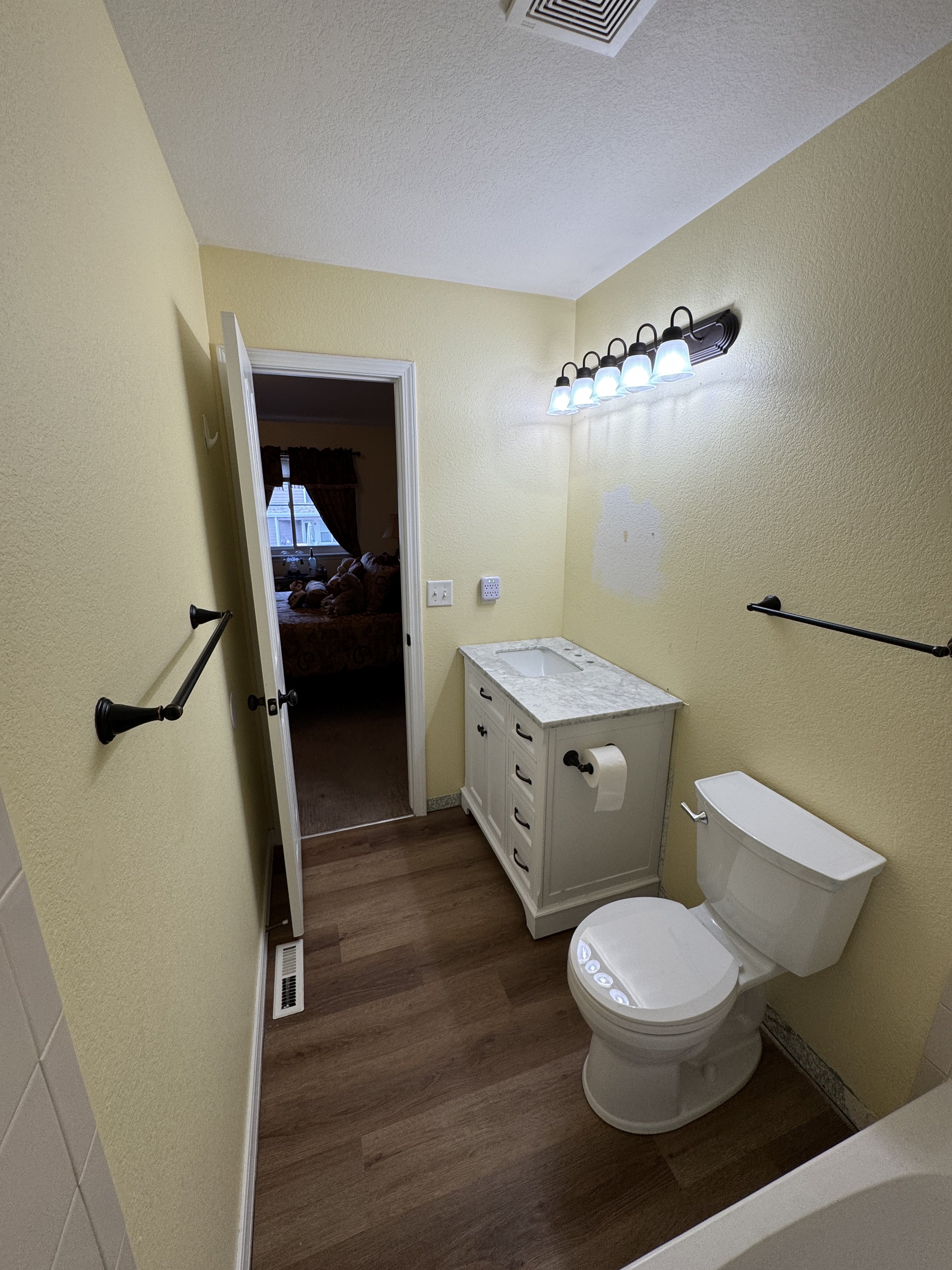 New bronze towel bars (18" and 24"), toilet paper holder, and vanity pulls.