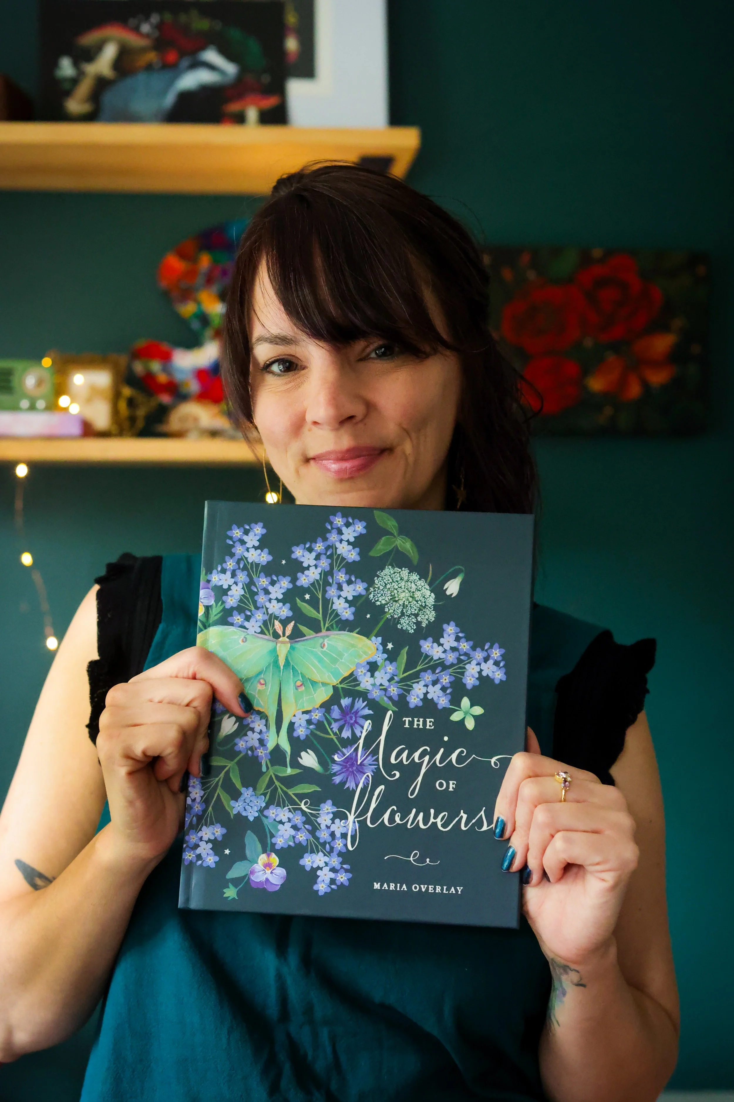 the magic of flowers book with artist woman holding it