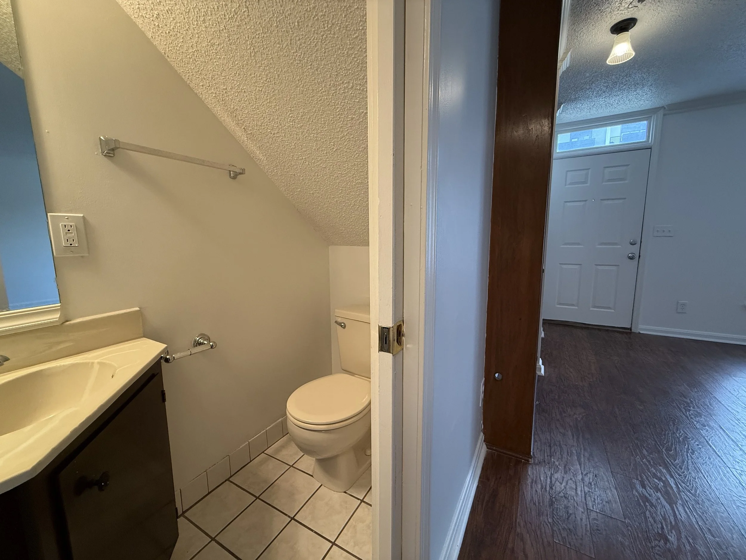 Bathroom with a toilet, dark vanity, beige countertop, and tiled floor.