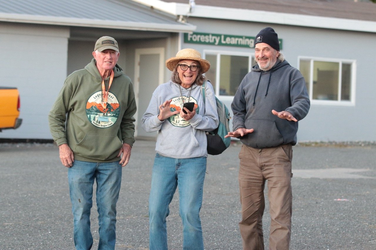 Three people standing outside in front of a building with a sign that reads 'Forestry Learning'.