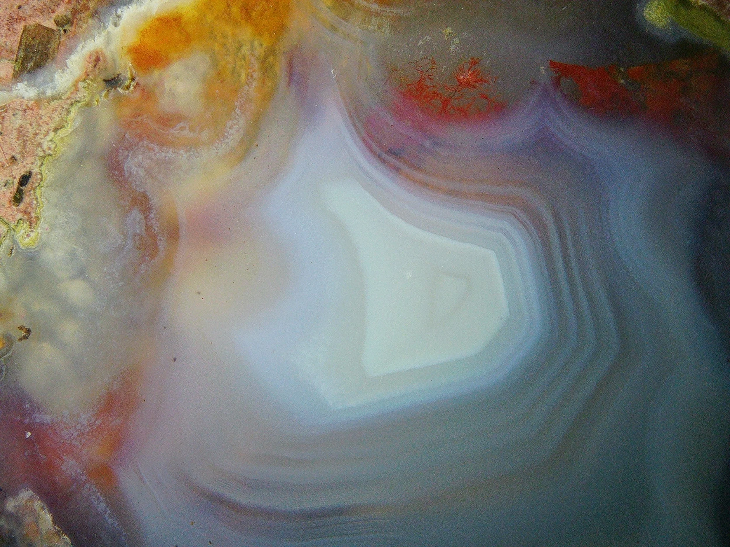 Close-up of a colorful abstract background with swirling patterns of white, pink, yellow, and orange hues.