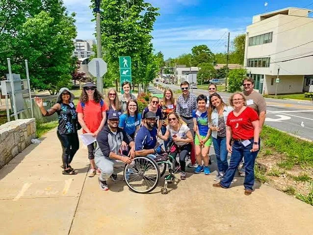 A group of community leaders gathers on a sidewalk during a walking tour