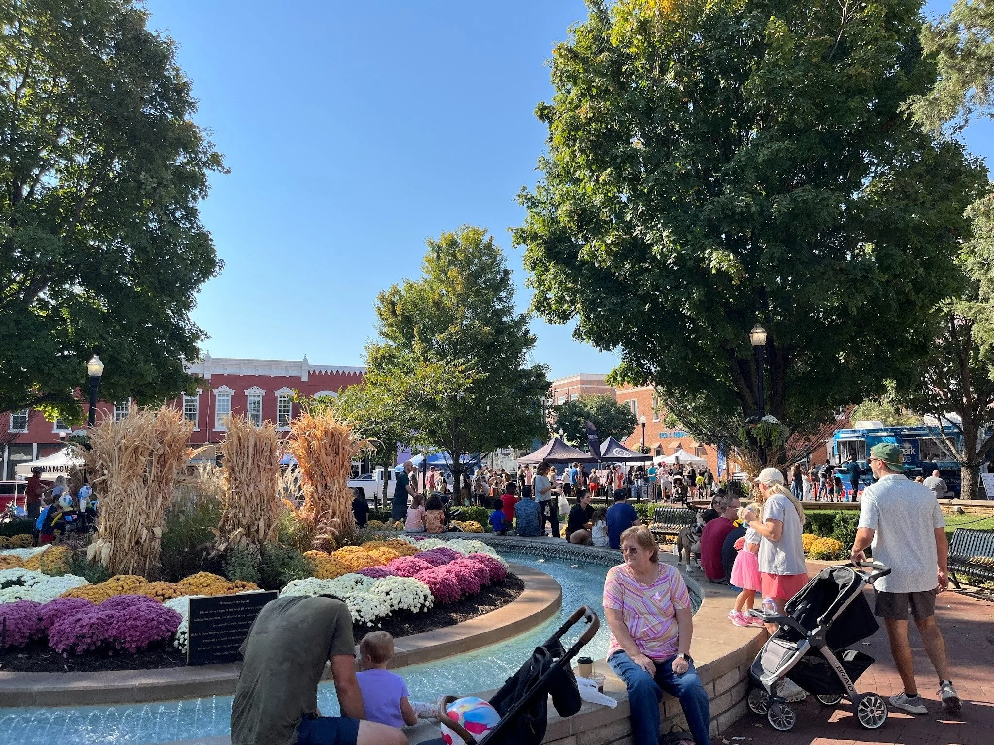 People gathered around the fountain and flower beds on the Bentonville town square