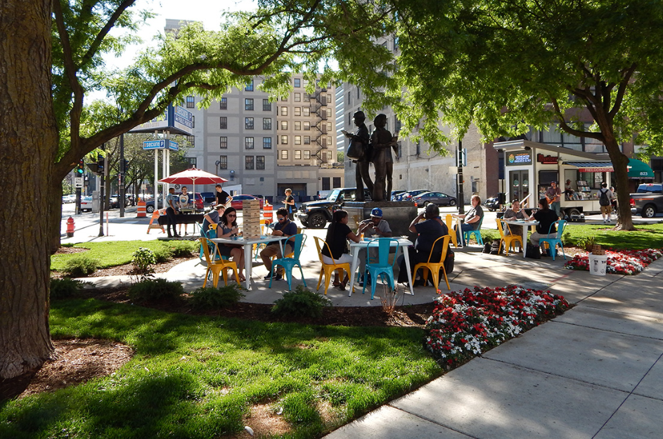 People gather at café tables in Postman Square, a downtown public space in Milwaukee, Wisconsin