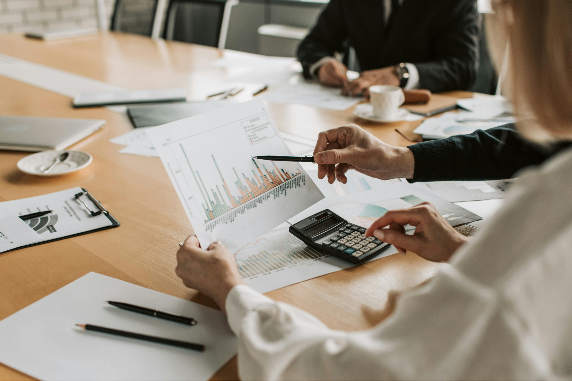 Business professionals reviewing bar graphs and financial data during a strategy meeting, illustrating data-driven decision-making in business growth consulting.