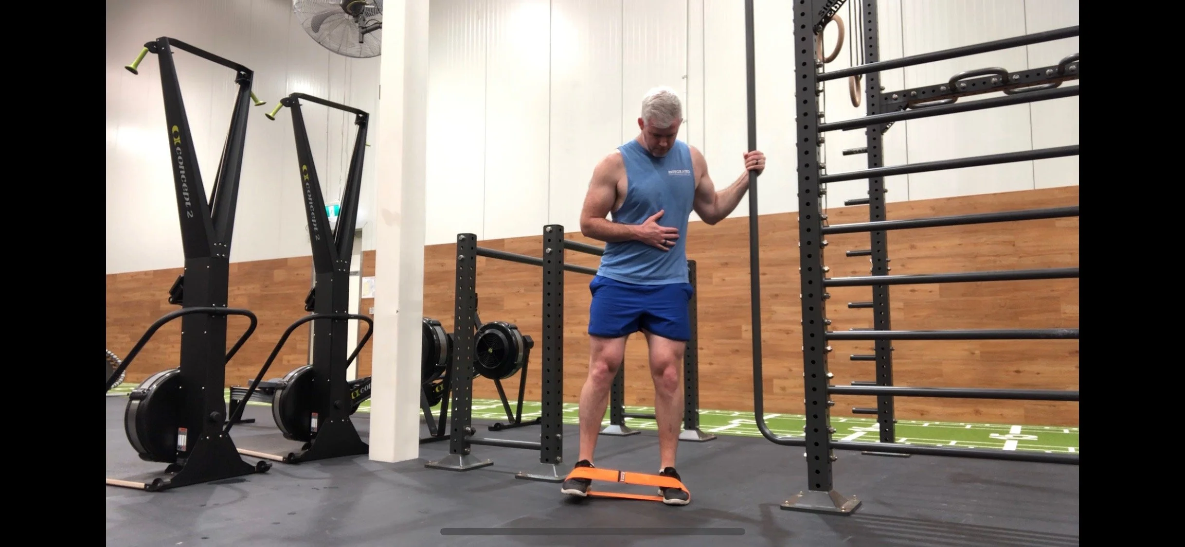 Man exercising with resistance band in gym by pull-up bars and machines