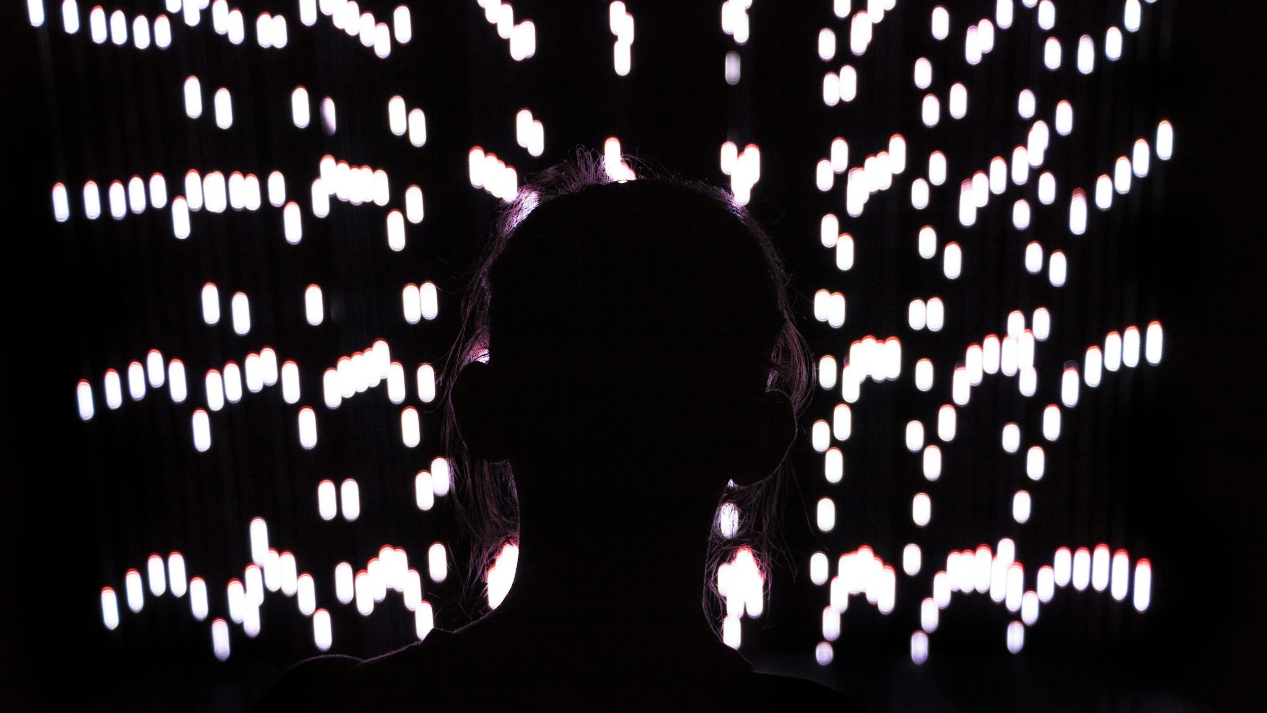 person in a dark room with interesting little lights