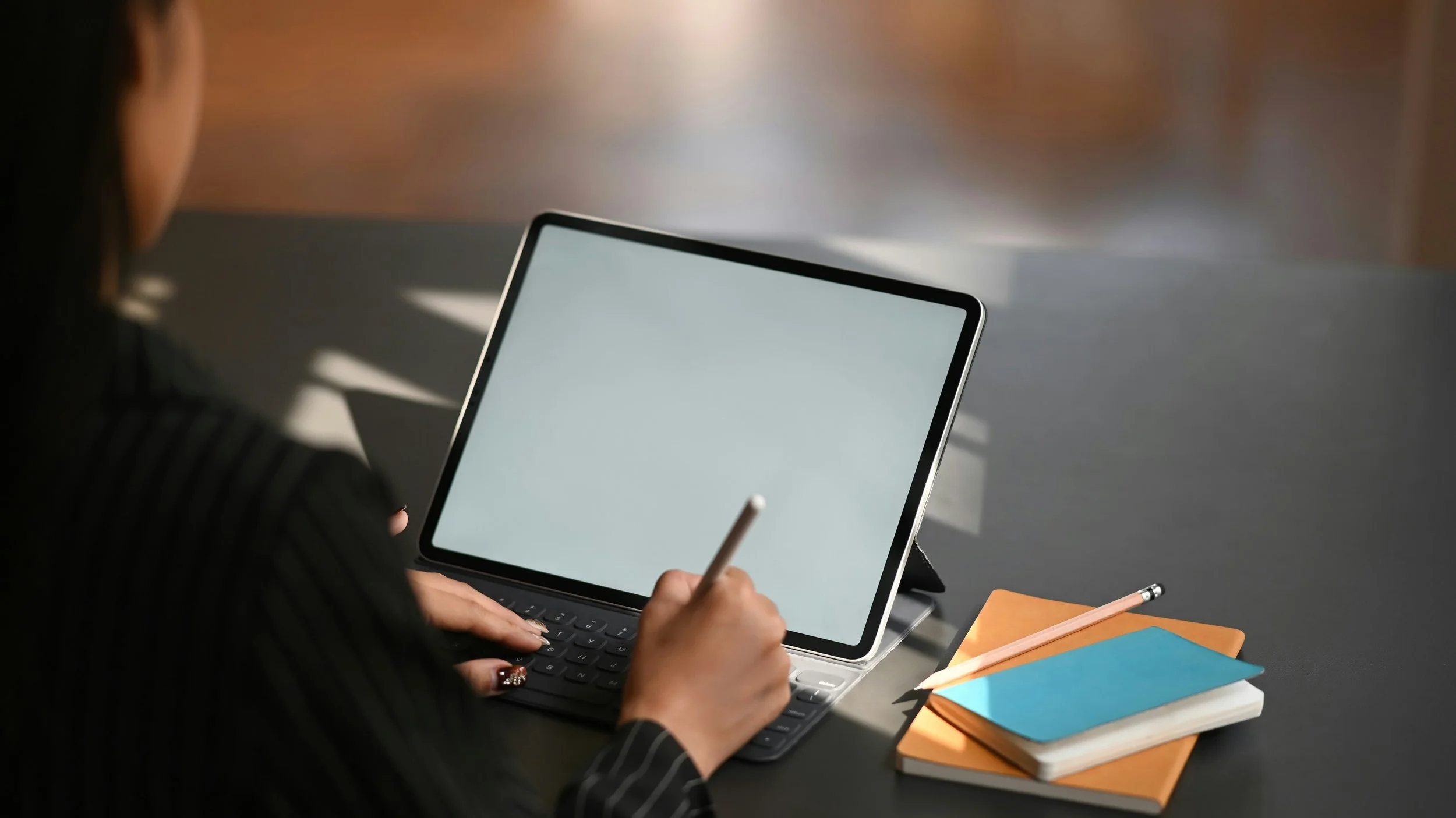 A woman using a tablet and keyboard