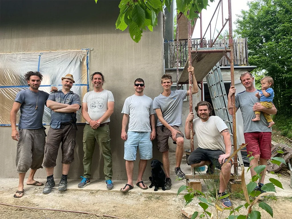 A szalmaotthonok csapata szalmabála hőszigetelésre felrakott mész-homok vakolat műhelymunka közben.
