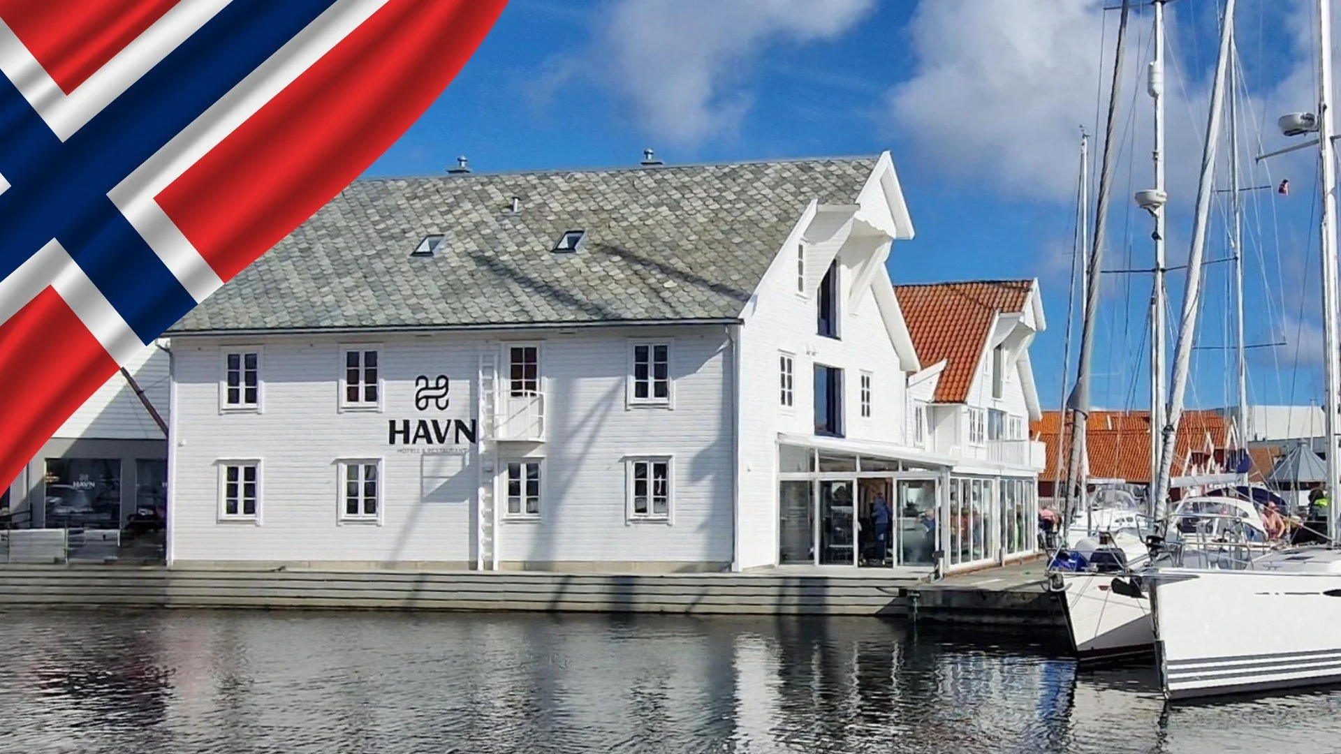 hvitt sjøhus med uteservering og norsk flagg